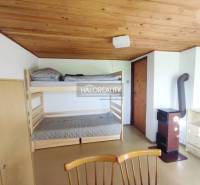 Ein Innenraum mit einem Etagenbett, einer Holzdecke, einem Schrank und einem Kachelofen in den Gärten.