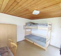 Einfaches Zimmer mit Holzvertäfelung an der Decke, einem Etagenbett und einem Schrank im Garten.