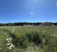 Grundstück zum Wohnen in Jamník mit Rasenfläche und Gebäuden im Hintergrund.