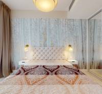 Schlafzimmer mit gemustertem Vorhang, Spiegelschrank und Lampe in einer 2-Zimmer-Wohnung.