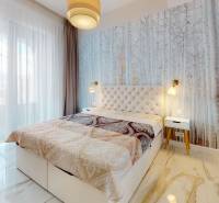 Schlafzimmer mit Naturmotiv auf der Tapete, großes Fenster und Spiegelschrank in einer 2-Zimmer-Wohnung.