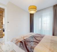 Schlafzimmer in einer 2-Zimmer-Wohnung mit Ziegelwand und Vorhang.