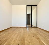 Ein Zimmer mit Holzboden und einem Spiegelschrank in einer 2-Zimmer-Wohnung.