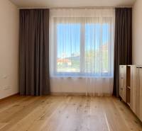 Geräumiges Zimmer mit Holzboden, Vorhängen und Kommode in einer 2-Zimmer-Wohnung.