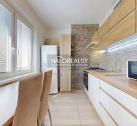 Küche in einer 3-Zimmer-Wohnung mit eingebautem Gerät, Holzschränken und Esstisch.