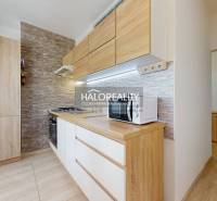 Küche in einer 3-Zimmer-Wohnung mit Holzmöbeln und Backsteinwandverkleidung, Geräte.