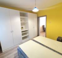Gelbes Schlafzimmer mit großem weißen Schrank in einer 3-Zimmer-Wohnung.