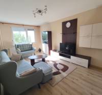 Wohnzimmer in einer 3-Zimmer-Wohnung mit Sofa, TV-Möbeln und Fenster im Hintergrund.