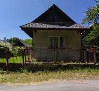 Ein Einfamilienhaus in Čelovce mit Garten, Zaun und Bäumen, sonniges Wetter.