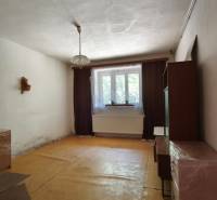 Ein Zimmer in einem Einfamilienhaus mit Möbeln und einem Fenster, Vorhänge ergänzen den Raum.