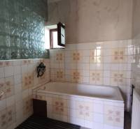 Ein Badezimmer in einem Einfamilienhaus mit Fliesen und einer Badewanne, dekoriert mit Vintage-Motiven.