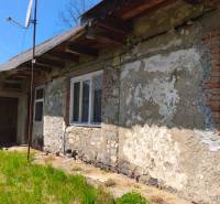 Ein Einfamilienhaus in Čelovce mit verputzter Wand und Satellitenschüssel im Hof.