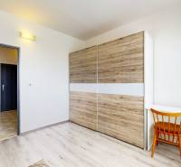 Ein Zimmer in einer 3-Zimmer-Wohnung mit einem Schiebeschrank, einem Schreibtisch und einem Stuhl.