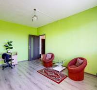 Helles Zimmer in einer 3-Zimmer-Wohnung mit Möbeln und dekorativem Teppich.