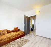 Ein Zimmer in einer 3-Zimmer-Wohnung mit einem Sofa, Holzboden und einem Einbauschrank.