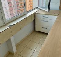 Loggia in einem Einzimmerapartment mit Blick auf die benachbarten Plattenbauten durch ein großes Fenster.