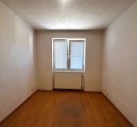 Ein leerer Raum mit Parkettboden und einem Fenster in einer 3-Zimmer-Wohnung.