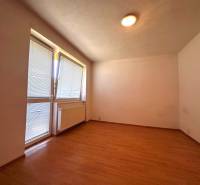 Ein Zimmer mit Holzboden, Heizkörper und Fenster mit Rollläden in einer 3-Zimmer-Wohnung.