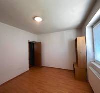 Ein leerer Raum in einer 3-Zimmer-Wohnung mit hellen Möbeln und einem großen Fenster.