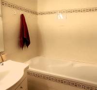 Badezimmer in einer 3-Zimmer-Wohnung mit Waschbecken, Spiegel und Badewanne.