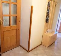 Der Flur in der 3-Zimmer-Wohnung mit Holzmöbeln und Dekoration in der Vase.