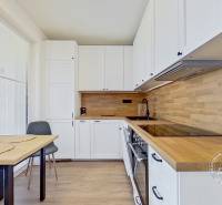 Eine Küche in einer Einzimmerwohnung mit einer Arbeitsplatte aus Holz und einem Esstisch.