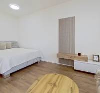 Schlafzimmer in einer Einzimmerwohnung mit Bett, Holztisch und minimalistischem Dekor.
