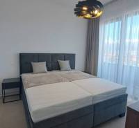 Schlafzimmer mit großem Bett und moderner Lampe in einer 2-Zimmer-Wohnung.