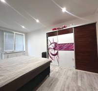 Schlafzimmer mit Bett, Einbauschrank und Fenstern in einer 2-Zimmer-Wohnung.