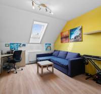 Dachzimmer in einem Einfamilienhaus mit bequemer Couch, Keyboard und Schreibtisch.