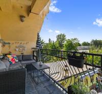 Der Balkon eines Einfamilienhauses mit bequemen Sitzgelegenheiten, Blick auf den Garten und Grünflächen.