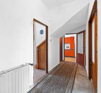 Der Flur im Einfamilienhaus mit Türen, die in die Küche mit der orangefarbenen Küchenzeile führen.