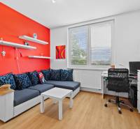 Wohnzimmer in einem Einfamilienhaus mit roter Wand, Sofa und Arbeitsecke.