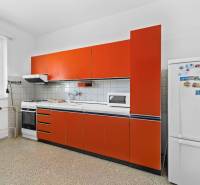 Küche in einem Einfamilienhaus mit Herd, Mikrowelle und orangefarbener Küchenzeile.