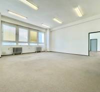 Ein hell erleuchteter Raum in einem Büro mit großen Fenstern und Heizkörpern.