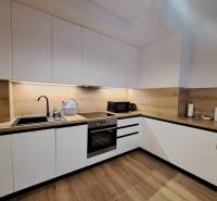 Küchenzeile in einer 2-Zimmer-Wohnung mit weißen Schränken und einer Holzarbeitsplatte.