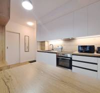 Küche in einer 2-Zimmer-Wohnung mit einer Arbeitsplatte aus Holz und weißen Schränken.