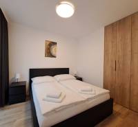 Schlafzimmer mit Doppelbett, Tischen und Schrank in einer Zweizimmerwohnung.