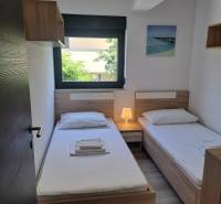 Ein Zimmer in einer 3-Zimmer-Wohnung mit zwei Betten, einem Nachttisch und einem Fenster mit Aussicht.