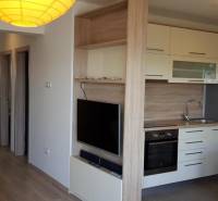 Küche in einer 3-Zimmer-Wohnung mit eingebauten Geräten und einem Fernseher an der Wand.