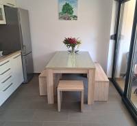 Essbereich in einer 3-Zimmer-Wohnung mit einem Holztisch, Blumen und einem Baumgemälde an der Wand.