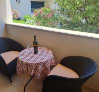 Der Balkon einer 3-Zimmer-Wohnung mit zwei Stühlen und einem Tisch mit Wein und Gläsern.