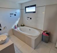 Badezimmer in einem Einfamilienhaus mit Badewanne, Waschbecken und Stauraum.