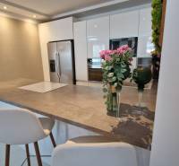 Küche in einem Einfamilienhaus mit Bartresen, Stühlen und Blumen auf dem Tisch.