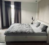 Schlafzimmer im Einfamilienhaus mit Bett, Vorhängen und Teppich, helle Zimmer.