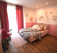 Kinderzimmer in einem Einfamilienhaus mit rosa Vorhängen und Blumendekoration an der Wand.