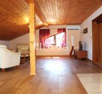 Dachgeschosswohnung mit Holzbalkendecke und Ledersitzmöbeln in einer 3-Zimmer-Wohnung.
