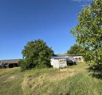 Grundstücke zum Wohnen in Povoda mit Rasenfläche und einem älteren Gebäude im Hintergrund.