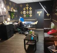 Innenraum eines Gebäudes mit einem Tattoo-Studio, goldene Dekorationen an den Wänden.