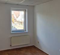 Ein Zimmer mit einem Fenster, einem Heizkörper und weißen Wänden in einem Gebäude.